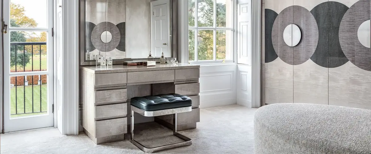 Dressing room with a leather topped stool at the dressing table and pale wardrobes inlaid with marquetry discs
